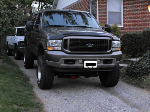 2003 Ford Excursion - This lifted 2003 Ford Excursion features a prominent Ford grille and aftermarket lighting, parked in a driveway.