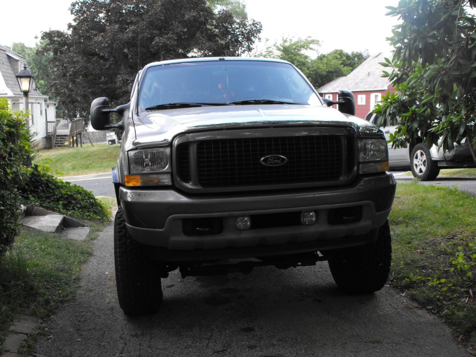 Front view of a gray lifted Ford Excursion SUV parked in a driveway
