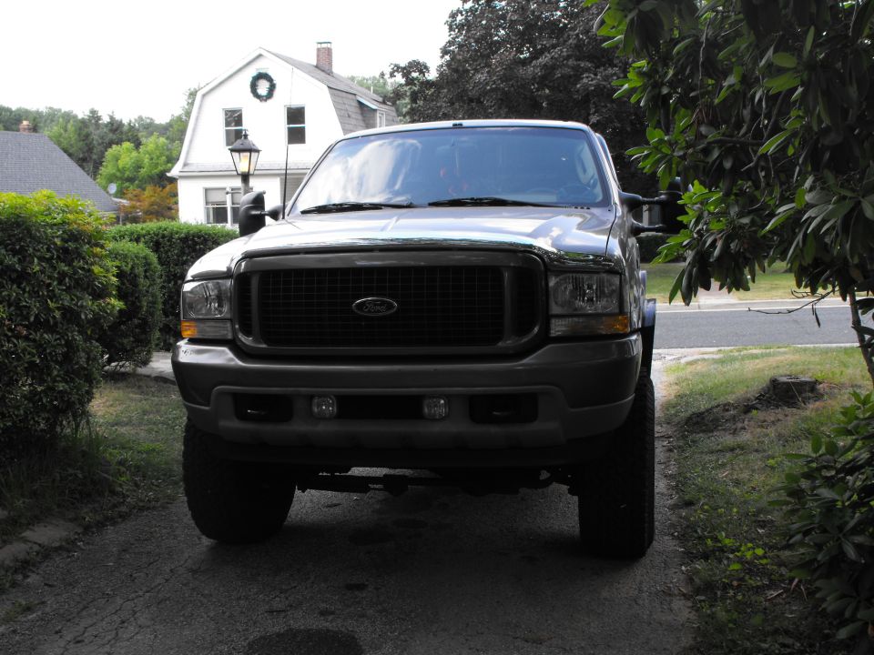 Front view of a dark Ford Excursion SUV on a driveway with lift and large tires
