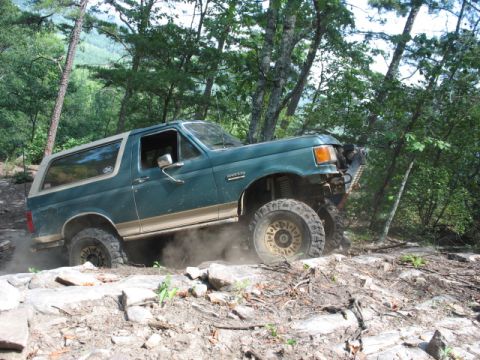 1978 Ford Bronco - This modified Ford Bronco is navigating a rocky, off-road trail surrounded by trees.