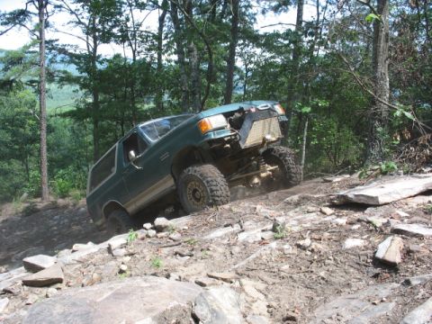 1978 Ford Bronco - Modified SUV navigates a challenging off-road trail with steep, rocky terrain.