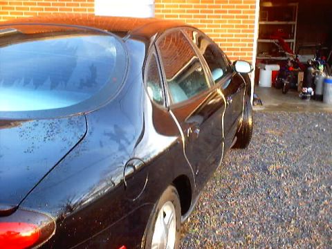 1999 Ford Taurus - A black sedan, possibly a 1998 model, is parked in a driveway with a garage in the background.