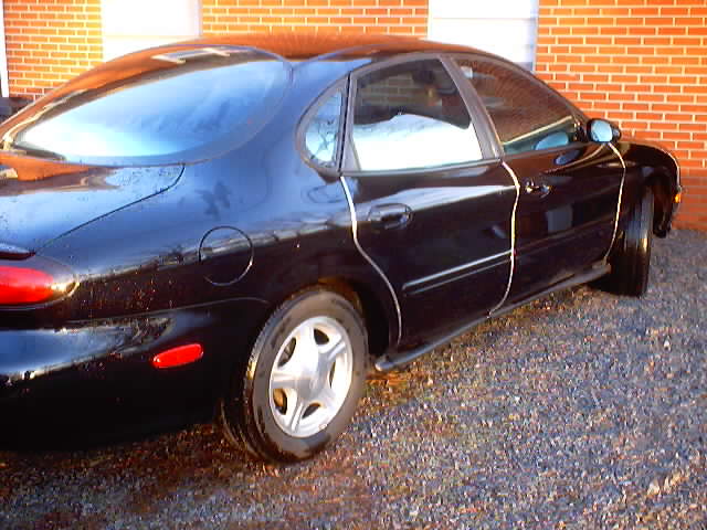 Black 1999 Ford Taurus sedan, rear quarter view