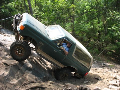 1978 Ford Bronco - A man drives a modified green Ford Bronco up a steep, rocky incline on an off-road trail.