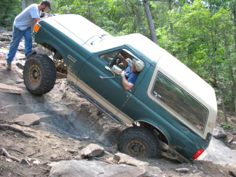 1978 Ford Bronco - An off-road enthusiast maneuvers a green and tan SUV through a challenging rocky landscape.