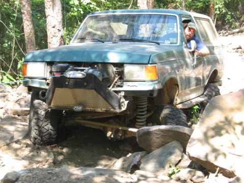 1978 Ford Bronco - Off-road SUV tackling a difficult rocky trail with a winch engaged.