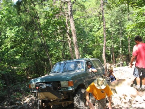 1978 Ford Bronco - A group of people are off-roading in a green SUV on a sunny day.