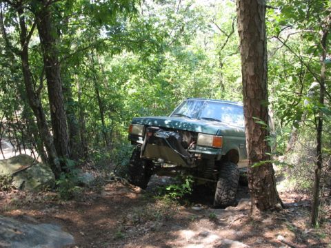1978 Ford Bronco - This modified SUV navigates a challenging off-road path through a wooded area.