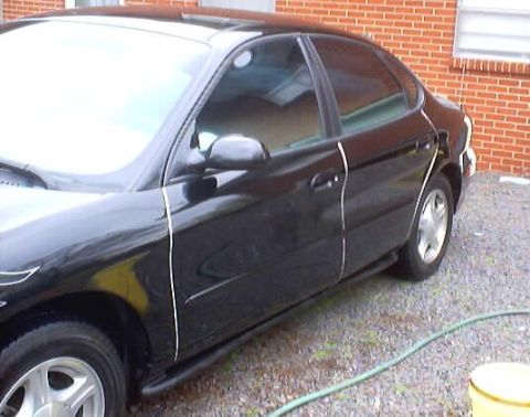 1999 Ford Taurus - A black 1999 Ford Taurus sedan is shown from a three-quarter front angle, parked outdoors.