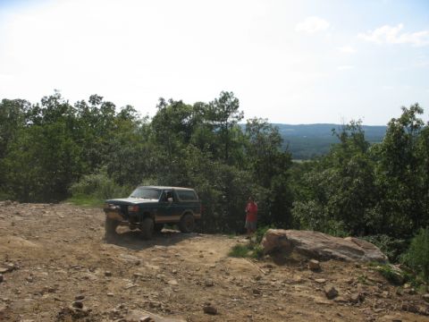 1978 Ford Bronco - A green SUV navigates a rough, rocky terrain with a person observing the scene.