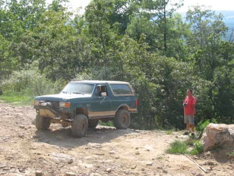 1978 Ford Bronco - Ford Bronco modified for off-road use on a rocky trail with a man observing.