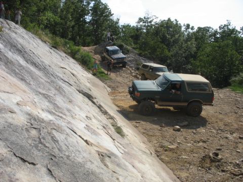 1978 Ford Bronco - Multiple SUVs navigate a challenging off-road trail with steep inclines and rocky terrain.