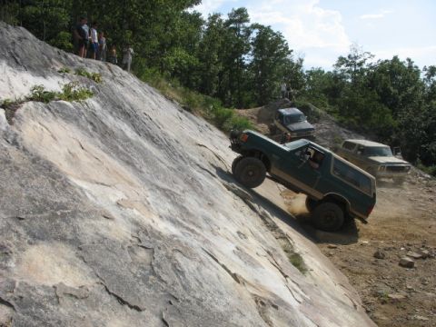 1978 Ford Bronco - Multiple off-road vehicles navigate a challenging rocky incline on a sunny day.
