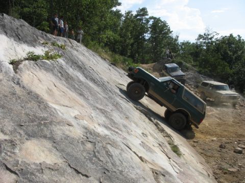 1978 Ford Bronco - Several off-road vehicles navigate a challenging rocky incline on a sunny day.