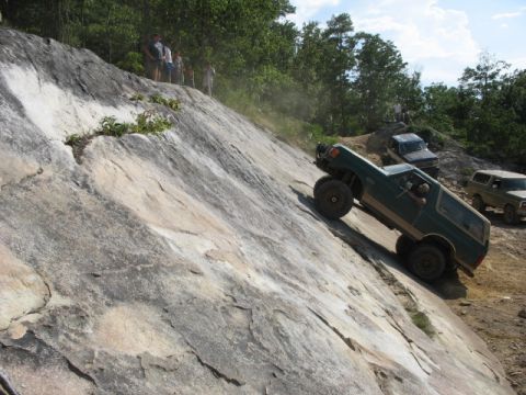 1978 Ford Bronco - An off-road enthusiast navigates a challenging rocky incline in a 1978 Ford Bronco, with spectators and other vehicles observing the ascent.