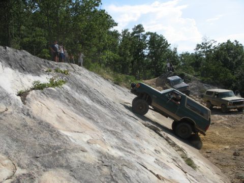 1978 Ford Bronco - Multiple off-road vehicles navigate a challenging rocky incline on a sunny day.