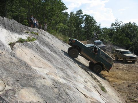 1978 Ford Bronco - A green 1978 Ford Bronco navigates a challenging rocky terrain, with other vehicles observing from a distance.
