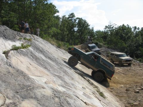 1978 Ford Bronco - Off-road vehicles tackle a challenging rocky incline on a sunny day.
