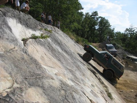 1978 Ford Bronco - Off-road vehicles navigate a challenging rocky terrain, with onlookers observing from the cliff edge.