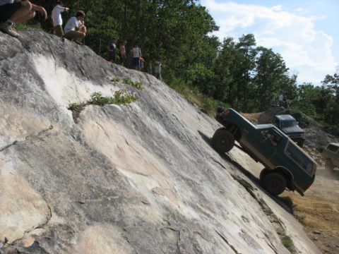 1978 Ford Bronco - A green 1978 Ford Bronco navigates a challenging rocky terrain, with onlookers observing the off-road adventure.