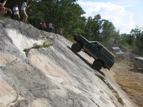 1978 Ford Bronco - An off-road SUV navigates a challenging rocky incline while spectators observe from above.