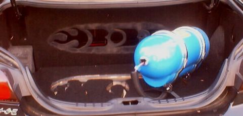1999 Ford Taurus - The trunk of a car is shown with a large blue nitrous tank installed.