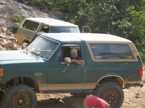 1978 Ford Bronco - Two Ford Broncos are parked on a dirt path, with one vehicle in the foreground and another partially visible behind it.