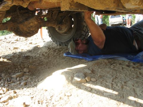 1978 Ford Bronco - A person works on the underside of a vehicle, with another SUV parked nearby.