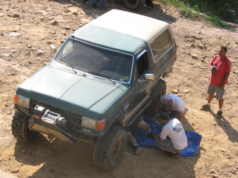 1978 Ford Bronco - Off-road Bronco undergoing maintenance on a dirt trail.