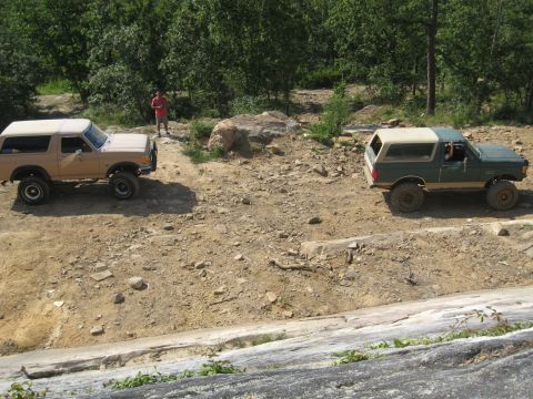 1978 Ford Bronco - Two Ford Broncos navigate a rocky, off-road trail under a sunny sky.