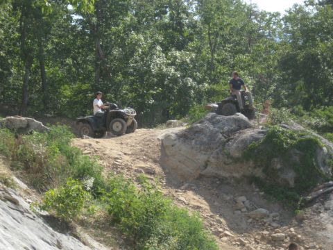 1978 Ford Bronco - Two ATVs navigate a challenging off-road trail on a sunny day.
