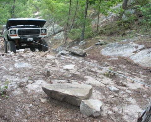 1978 Ford Bronco - 1978 Ford Bronco winching itself up a steep, rocky trail in a wooded area.