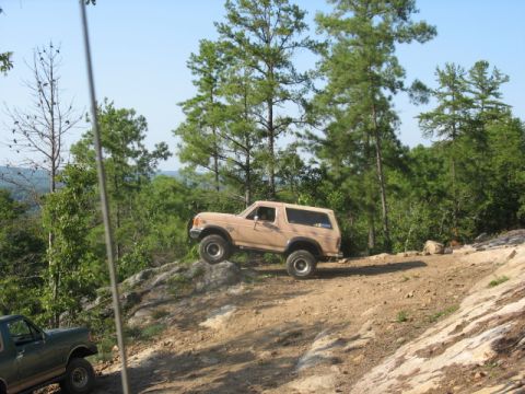 1978 Ford Bronco - A tan Ford Bronco navigates a challenging off-road trail, with another vehicle visible below.