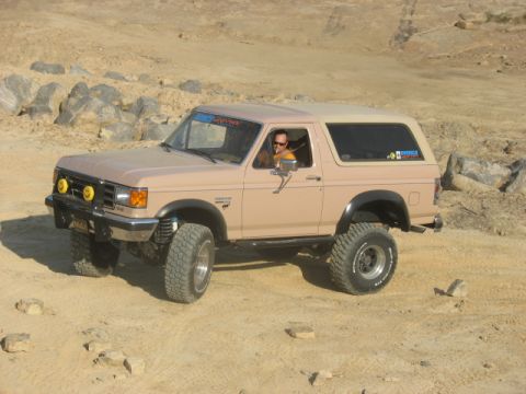 1978 Ford Bronco - A driver navigates a tan Ford Bronco through a rocky, off-road terrain.