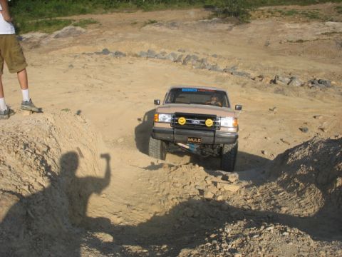 1978 Ford Bronco - Tan Ford Bronco navigates a dirt trail with a shadow of a person in the foreground.