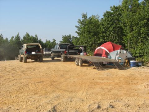 1978 Ford Bronco rear view, tan top, green body, lifted suspension, parked on dirt