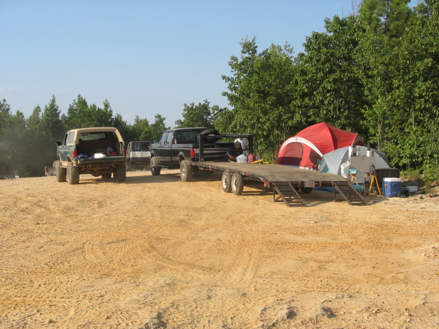 1978 Ford Bronco rear view, tan top, green body, lifted suspension, parked on dirt