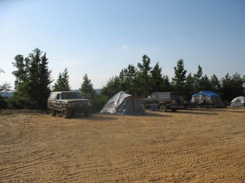 Two SUVs parked at a campsite with tents set up