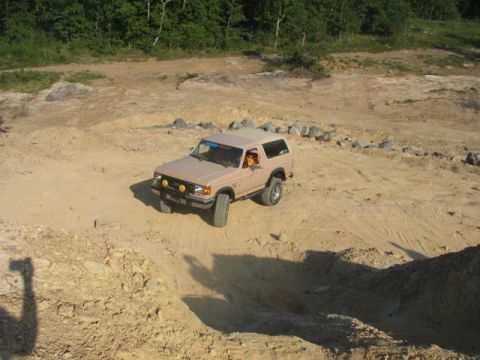 Tan SUV with aftermarket lights driving on a dirt track