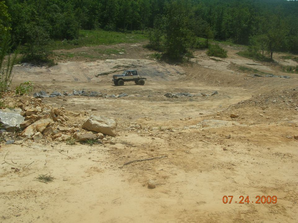 1991 Ford F-150 pickup truck, light-colored, driving on a dirt track in a quarry