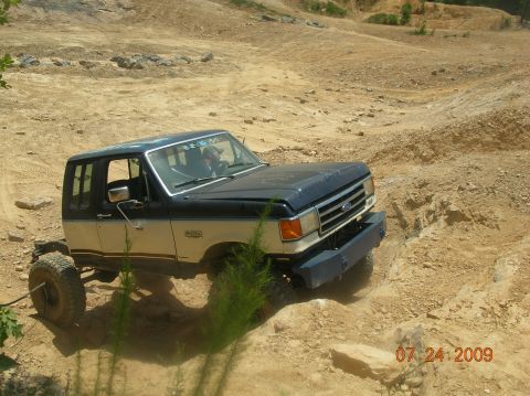 1991 Ford F-150 - This modified Ford Bronco navigates a challenging off-road course with large tires and a lifted suspension.