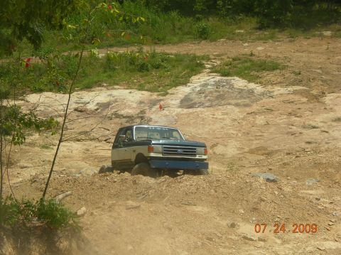 1991 Ford F-150 - A 1991 Ford F-150 navigates a challenging off-road terrain with a blue bumper and two-tone paint.
