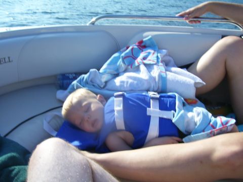 1991 Ford Bronco - A child sleeps peacefully on a boat, wearing a life vest and covered with blankets.
