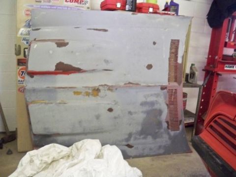1974 Pontiac Firebird - A car hood is shown in a garage, with visible signs of wear and tear, including rust and peeling paint.