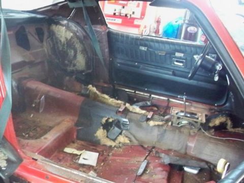 1974 Pontiac Firebird - The interior of a car shows significant wear and tear, with upholstery removed and insulation exposed.