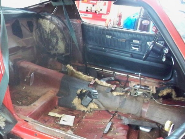 car interior with torn upholstery and exposed insulation, showing dashboard and door panel