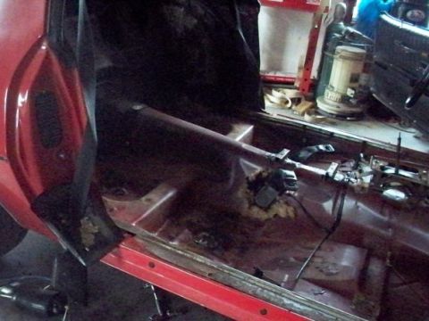 1974 Pontiac Firebird - Interior view of a red car showing floor rust and missing components.