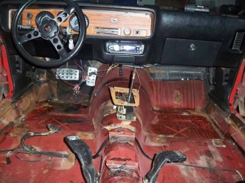 1974 Pontiac Firebird - The interior of a car shows a stripped red floor, dashboard, and steering wheel, indicating a restoration project.