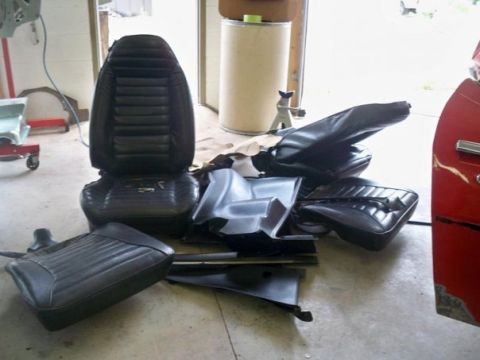 1974 Pontiac Firebird - Various black car interior components are disassembled and scattered on the concrete floor.