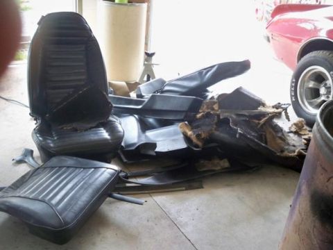 1974 Pontiac Firebird - Disassembled car interior components are piled on a garage floor next to a red vehicle.